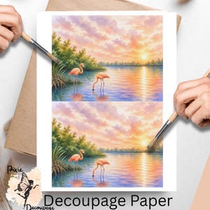 May include: Decoupage paper featuring a watercolor painting of two flamingos in a serene waterscape at sunset. The artwork showcases a vibrant sky with pink, orange, and yellow hues, and the text "Decoupage Paper" is visible.