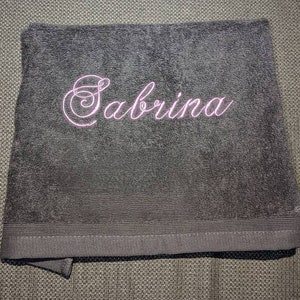 May include: A black towel with the name "Sabrina" embroidered in pink.