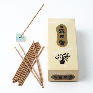 May include: A box of Morning Star Palo Santo incense sticks with a light brown background and black text. The box features a black and white illustration of a bonsai tree. The text on the box reads "Morning Star" and "Palo Santo Incense". The box is open and a bundle of incense sticks is visible. The incense sticks are brown and have a light brown holder.