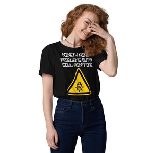 May include: Black t-shirt with the text "NINETY NINE PROBLEMS BUT A SOUL AIN'T ONE" in white, above a yellow hazard sign with a UV symbol. The shirt is paired with blue jeans.