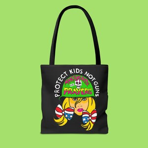 May include: Black tote bag with a white graphic of a girl wearing a green army helmet with the text "Protect Kids Not Guns" and "Thoughts and Prayers" on it. The girl is wearing a red, white, and blue bow on each side of her head.