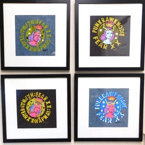 May include: Four framed art prints with black frames. Each print features a circular design with a stylized female figure wearing a crown, surrounded by text. The backgrounds vary in color, including denim and black.