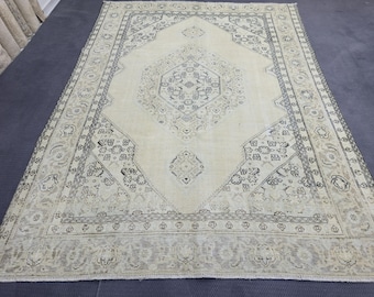 May include: A rectangular area rug featuring a cream-colored field with a central diamond-shaped medallion in dark gray. The rug displays intricate geometric and floral patterns throughout the border and center, finished with short fringe at both ends.