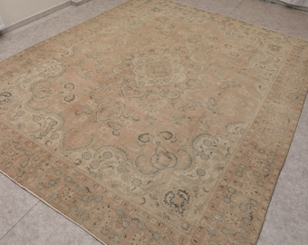 May include: A vintage rug with a beige background and intricate floral patterns in shades of brown and blue. The rug has a worn and faded look, giving it a rustic and antique feel.