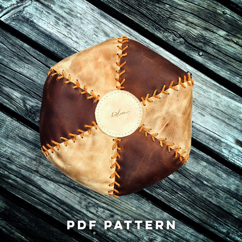 May include: A brown and tan leather pouf with a circular patch in the center that says "Katelyn". The pouf is stitched together with orange thread.
