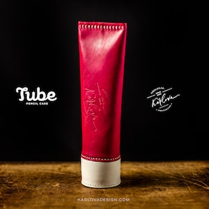Op de afbeelding: Een rode leren potlood etui met witte stiksels en een witte leren bodem. De etui is gelabeld "Tube Pencil Case" en heeft de tekst "Original Since 2014 Karlova" in een cirkel aan de zijkant.