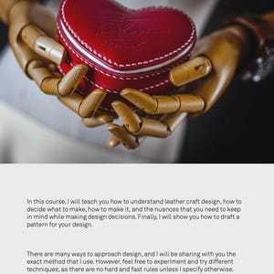 May include: A wooden hand model holding a red heart-shaped leather box with white stitching. The box has the word "Love" embossed on the front.
