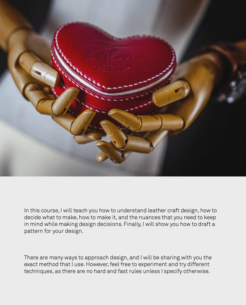 May include: A wooden hand model holding a red heart-shaped leather box with white stitching. The box has the word "Love" embossed on the front.