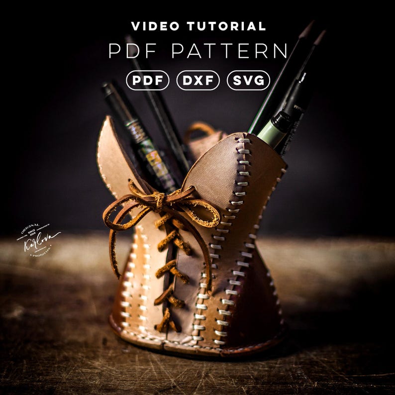 May include: A leather pencil holder featuring a corset-style design with brown leather lacing and white stitching. The text VIDEO TUTORIAL, PDF PATTERN, PDF, DXF, and SVG are visible. Several pens and pencils are stored inside the container.