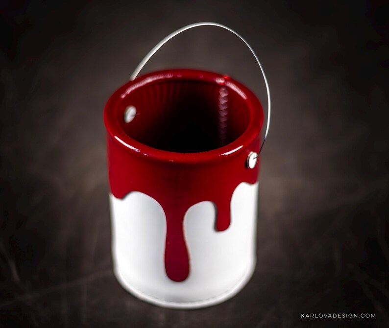 Peut inclure: Un petit pot de peinture blanc avec un couvercle en m&eacute;tal rouge et une coul&eacute;e de peinture rouge sur le c&ocirc;t&eacute;. Le pot a une poign&eacute;e en fil d'argent.