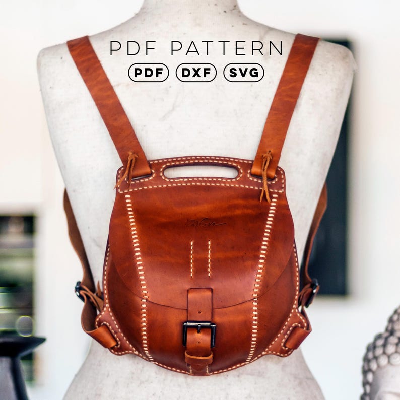 Op de afbeelding: Een lichtbruine leren rugzak met een handvat, twee schouderbanden en een voorflap die wordt vastgezet met een zwarte metalen gesp. Het ontwerp heeft zichtbare witte stiksels langs de randen. Tekst: PDF PATTERN, PDF, DXF, SVG.