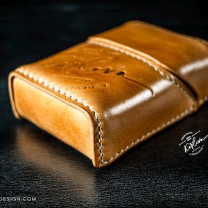 May include: A tan leather case with a hinged lid and visible white stitching along the edges. The surface features an embossed script logo that reads Karlova, with additional text reading Original Since 2018 Karlova Products and Karlovadesign.com.