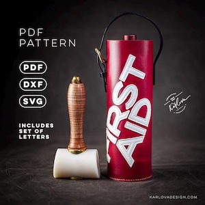 Puede incluir: Un botiquín de primeros auxilios de cuero rojo con costuras blancas y las palabras "FIRST AID" en letras blancas. El botiquín está al lado de un mazo de cuero con una cabeza blanca y un mango de madera.