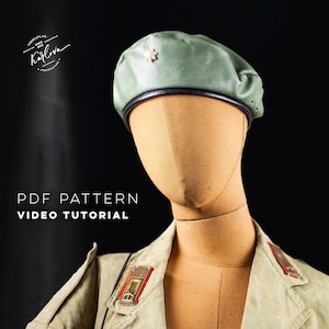 Peut inclure: Un béret en cuir vert avec une bande en cuir noir et une épingle en étoile dorée. Le béret est sur un mannequin portant un uniforme militaire vert avec des boutons dorés.