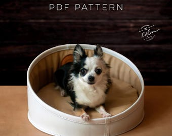 May include: A white circular pet bed with a tan interior cushion, featuring a small black and white long-haired dog sitting inside. The text PDF PATTERN is visible at the top, and a circular logo with the text Karlova is on the right.