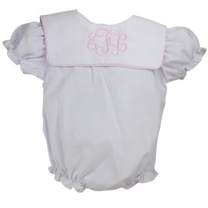 May include: White baby romper with a pink sailor collar and a pink embroidered monogram "F.C."
