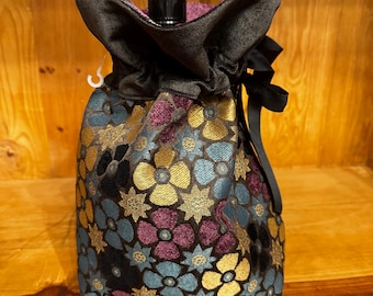 Sacchetto regalo per liquori di medie dimensioni a tema Flower Power anni '60: arazzo in ciniglia nera con un tocco di colore dato da un motivo floreale oro, blu e viola.