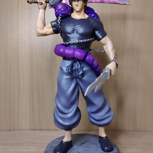May include: A black and grey action figure of a man with a purple worm wrapped around his torso. He is holding a sword in one hand and a knife in the other. The figure is standing on a grey base.