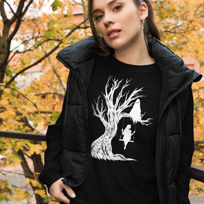 May include: Black t-shirt with a white graphic of a ghost sitting on a tree branch with a person on a swing. The text on the tree reads "Don't let the good times pass you by".