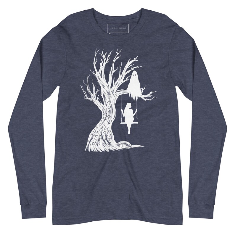 May include: A navy blue long-sleeve t-shirt with a white silhouette of a tree with a ghost and a person on a swing. The tree is covered in words, including "SPELL", "HIDDEN", "SAY", "SHE", "ART", "TO", "GOD", "SO", "FAR", "AND", "YOU".