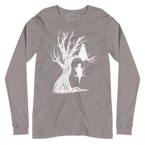 May include: A long-sleeved t-shirt in a heather grey color with a white graphic design of a tree with a ghost and a person on a swing. The tree has words written on it.