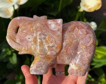 May include: A pink and white carved elephant figurine made of agate. The elephant is standing on all four legs with its trunk raised. The figurine is about 4 inches tall.