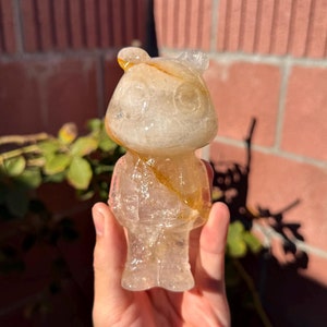 Puede incluir: Una figurita transparente y translúcida de un oso con un patrón de espiral amarillo y naranja. La figurita está hecha de un material que se asemeja al hielo.