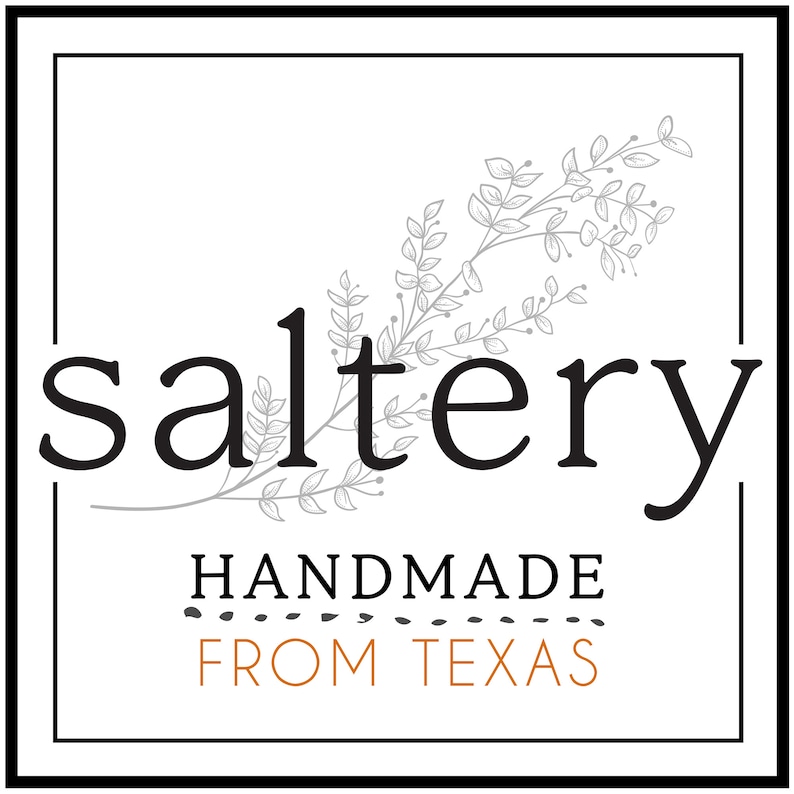 May include: A black and white logo with the word "saltery" in a stylized font. The logo is surrounded by a gray floral design. The text "HANDMADE FROM TEXAS" is below the logo.
