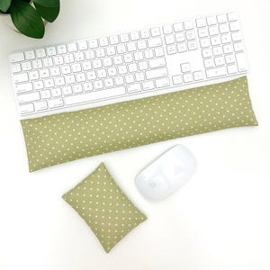 May include: A white wireless keyboard, mouse, and a green polka dot wrist rest and mouse pad set. The wrist rest is long and rectangular, and the mouse pad is square. The set is designed to provide comfort while working at a computer.