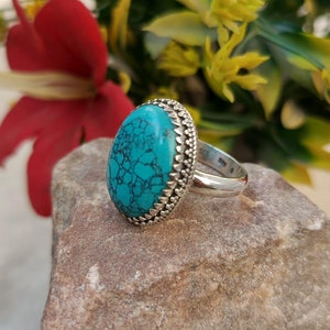 Puede incluir: Un anillo de plata con una piedra ovalada turquesa engastada en una banda de plata decorativa.