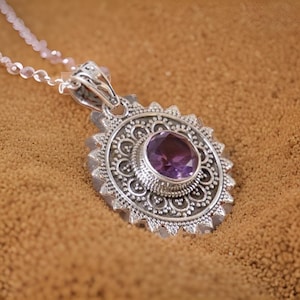 Può includere: Una collana con un ciondolo in argento con un intricato design a filigrana e una pietra preziosa di ametista rotonda di colore viola.