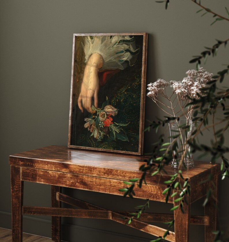 Pu&ograve; includere: Un dipinto incorniciato di una mano di donna che tiene un mazzo di fiori. I fiori sono un mix di rosso, rosa, bianco e giallo. La mano della donna indossa un polsino bianco. Lo sfondo &egrave; verde scuro e dorato.