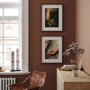 Pu&ograve; includere: Due stampe d'arte incorniciate con sfondo marrone. La stampa superiore mostra una mano che tiene un mazzo di fiori. La stampa inferiore mostra una mano che tiene un singolo fiore rosso.