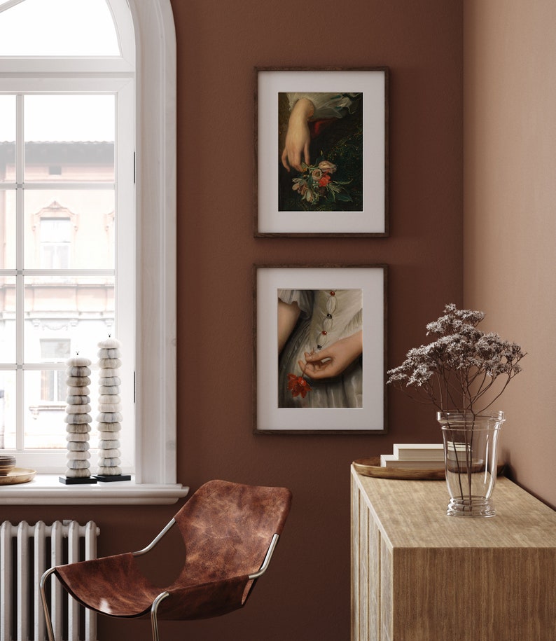 Pu&ograve; includere: Due stampe d'arte incorniciate con sfondo marrone. La stampa superiore mostra una mano che tiene un mazzo di fiori. La stampa inferiore mostra una mano che tiene un singolo fiore rosso.