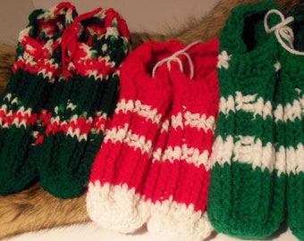 May include: Three pairs of crocheted slipper socks in red, white, and green. The slippers are striped and have a simple design.