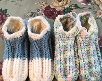May include: Two pairs of crocheted slipper socks. One pair is blue and white, the other is a multi-colored mix of pink, blue, and green.