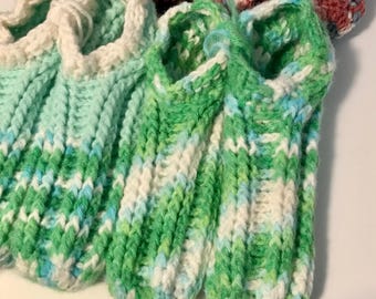 May include: A pair of green, white, and blue crocheted slippers. The slippers have a soft, fuzzy texture and are perfect for keeping your feet warm.