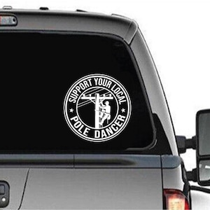 May include: A white vinyl decal sticker for a car window. The sticker features a circle with the text "Support Your Local Pole Dancer" and a silhouette of a person climbing a utility pole.