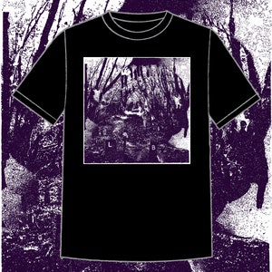 以下が含まれることがあります： 白い森のシーンのグラフィックプリントが施された黒いTシャツ。グラフィックには、下部に「L」と「B」の文字があります。