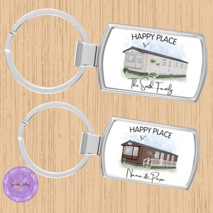 May include: Two silver keyrings with rectangular tags. The top tag has a watercolour illustration of a mobile home with a blue sky and the text "HAPPY PLACE The Smith Family". The bottom tag has a watercolour illustration of a mobile home with a blue sky and the text "HAPPY PLACE Nana & Papa".