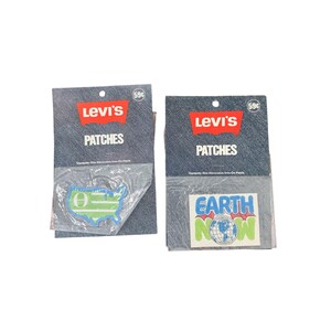 May include: Two Levi's brand iron-on patches in original packaging. One patch is a green and blue map of the United States with a Greek letter. The other is a rectangular patch with the text Earth Now and a globe graphic. Both cards say 59 cents.