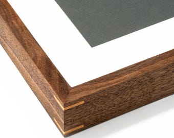 May include: Close-up of a wooden picture frame with a dark gray mat and white border. The frame is made of oiled walnut and has a natural wood grain. The text "Oiled Walnut" is at the bottom.