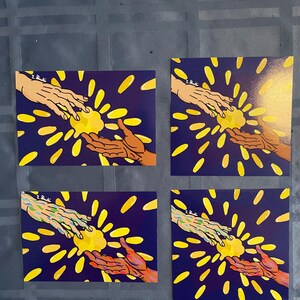 May include: Four square prints with a dark blue background and yellow rays of light emanating from the center. Two hands reach towards each other from opposite sides of the image, touching in the center. The hands are different colors in each print.
