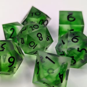 Könnte beinhalten: Ein Satz grüner und schwarzer Würfel mit wirbelnden Mustern. Die Würfel sind aus durchsichtigem Kunststoff und haben schwarze Zahlen auf jeder Seite.