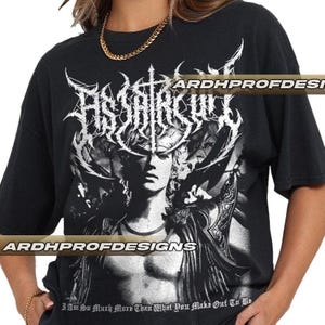 Könnte beinhalten: Schwarzes T-Shirt mit einer detaillierten weißen Grafik, die eine stilisierte Figur und den Text "ASSAR CULT" zeigt. Das Design umfasst verzierte, gotische Schriftzüge und Bilder. Das Shirt hat auch den Text "I Am So Much More Than What You Make Out To Be".