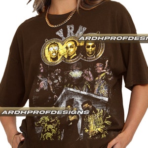 以下が含まれることがあります： ゴールドのチェーンとサングラスをかけた人々のグループのヴィンテージスタイルのグラフィックプリントが施されたブラウンのTシャツ。プリントには「Y.R.N.」の文字が含まれています