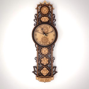May include: Wooden wall clock with a natural wood finish, featuring a round clock face and a decorative frame. The clock displays chakra symbols and the text "SEVEN LIGHTS, ONE SOUL". The clock measures approximately 24 inches in height.
