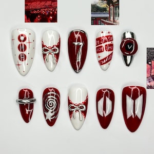 May include: A collection of ten artificial nails in various designs. The nails feature a color palette of red, white, and silver. Some nails have bow accents, while others display the number 7, text, or a logo. Two small images are also included.