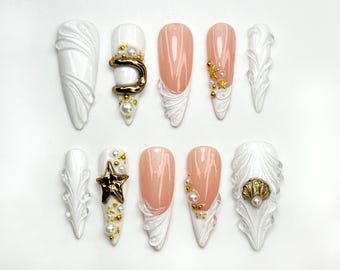 May include: Set of ten false nails with a white and pink base. The nails are decorated with gold accents, pearls, and seashells.