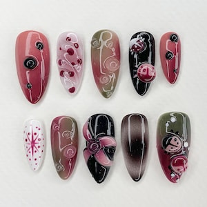 Könnte beinhalten: Zehn verschiedene Nageldesigns mit verschiedenen Farben, Mustern und Texturen. Die Designs beinhalten Wirbel, Punkte, Marienkäfer und eine Blume.